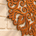 Close-up van de roeststructuur, sierlijke uitsparingen en zwarte bevestigingsschroef van de mandala.