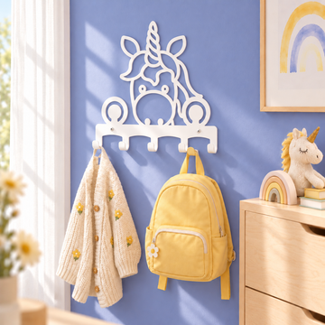 Witte metalen eenhoornkapstok aan een lavendelblauwe muur, met een crème vest en zachtgele kinderrugzak.