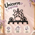 Zwarte unicorn kapstok met iconen en de teksten stevig staal, uniek design en vijf haken tegen een zachtroze muur.